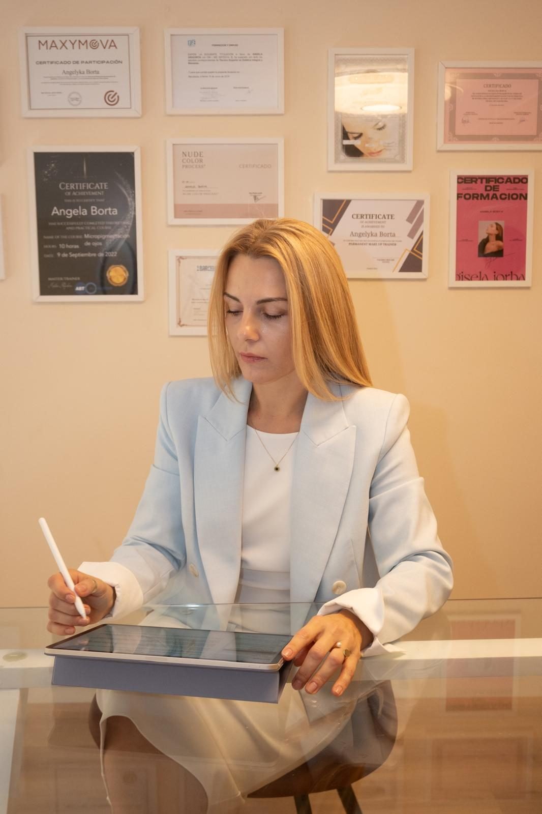 Angela Borta trabajando en su estudio frente a la pared de certificaciones